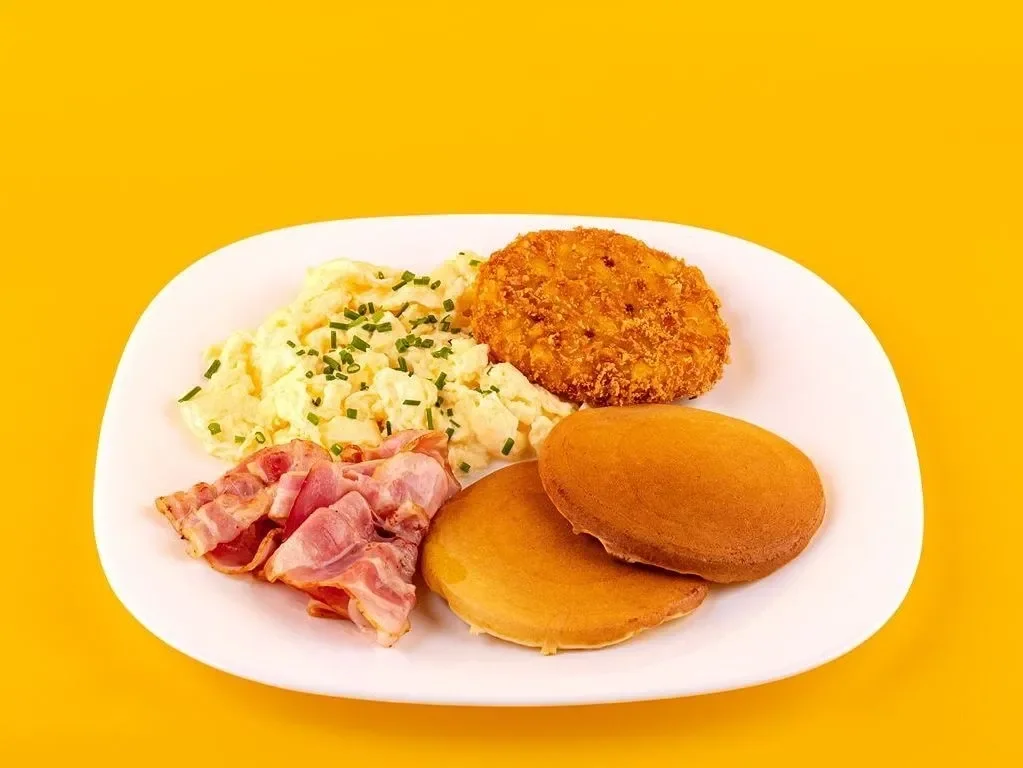 Snídaňový talíř s vejci, slaninou, lívanci a hash brownem
