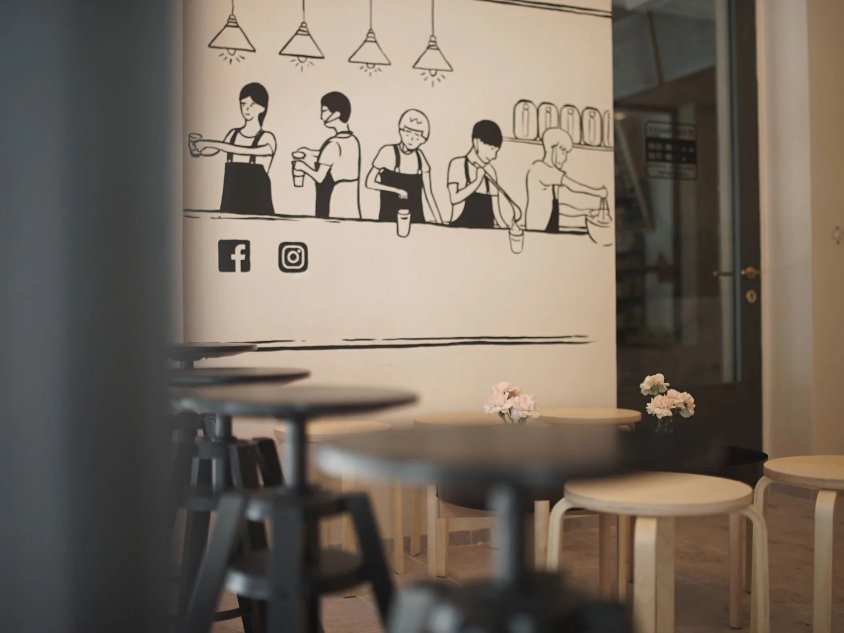 Detail interiéru: nástěnná kresba baristů a stolky se stoličkami