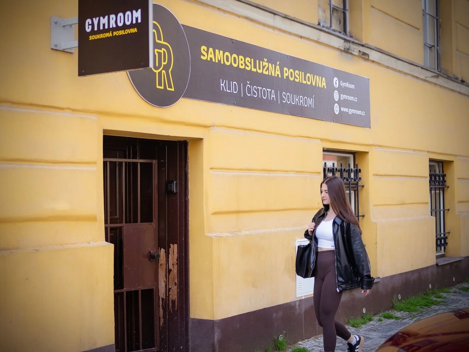 Vchod pobočky GymRoom Nusle s reklamní tabulí Samoobslužná posilovna