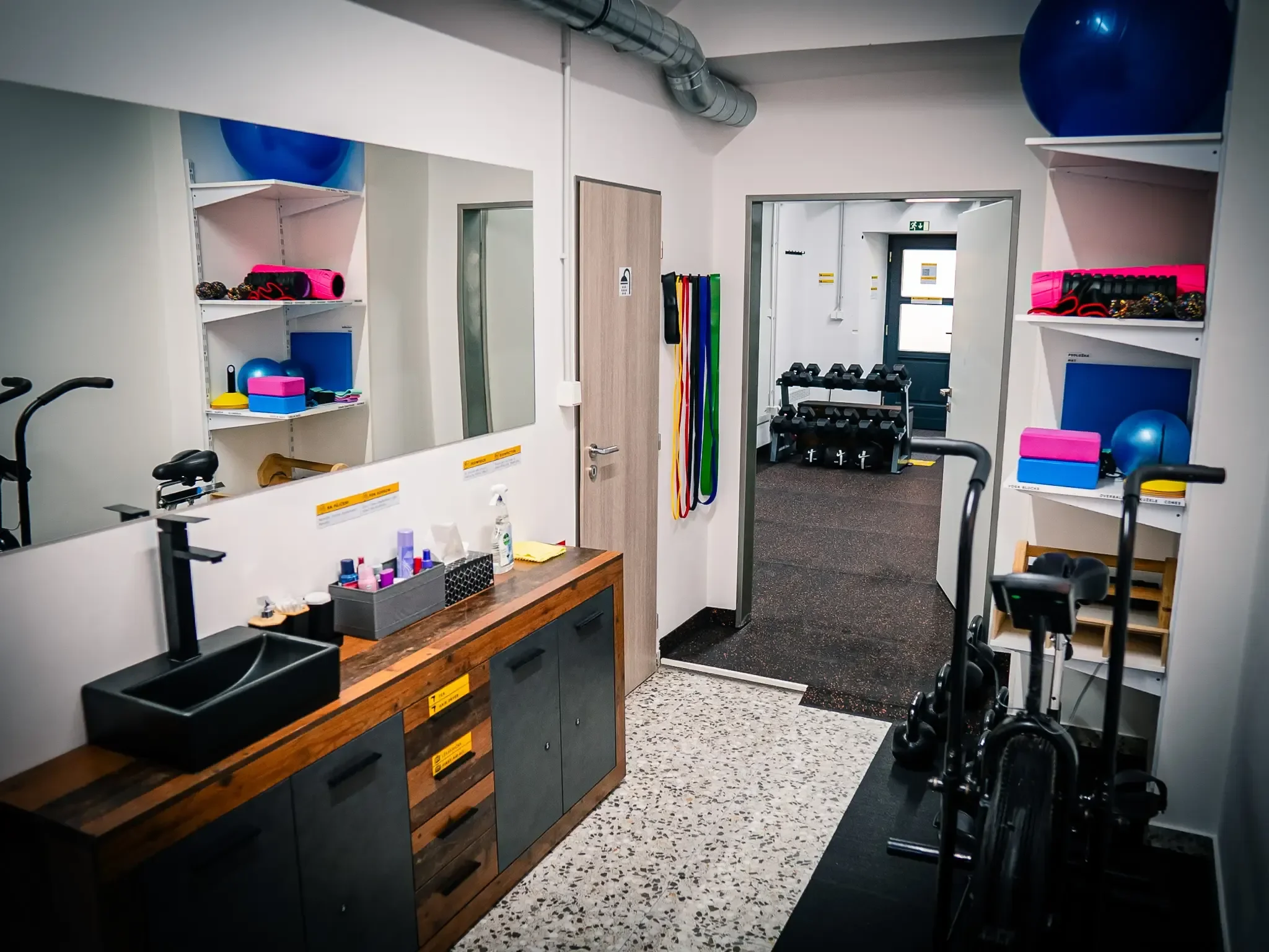 Zázemí pobočky GymRoom: umyvadlo, pomůcky na cvičení a vstup do tréninkového sálu