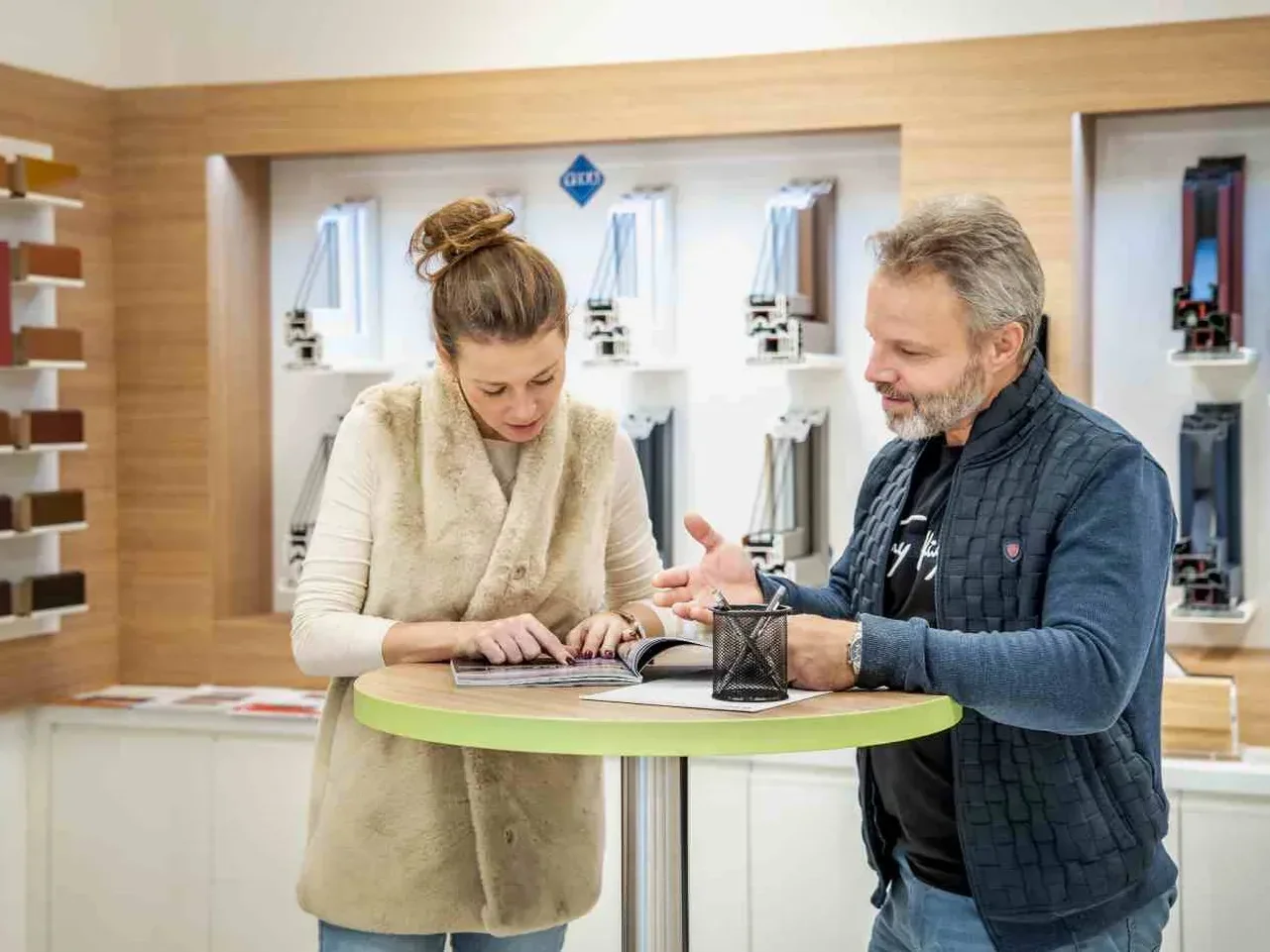 Jednání se zákazníkem v showroomu u stěny se vzorky okenních profilů
