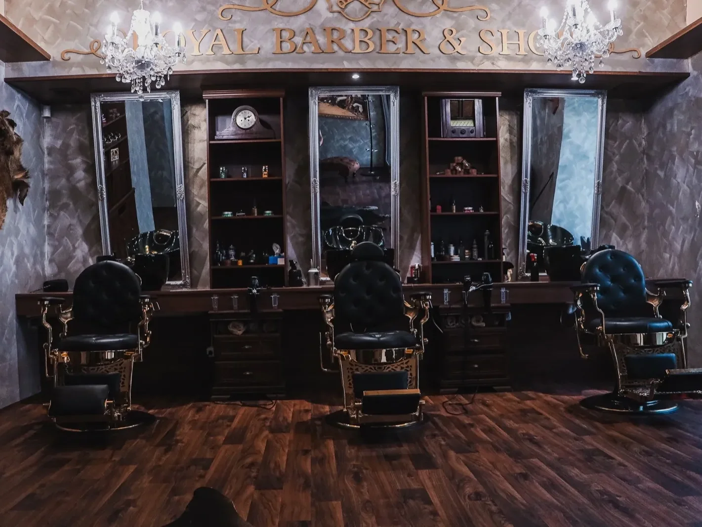 Interiér pobočky se třemi křesly a zrcadly pod nápisem Royal Barber & Shop