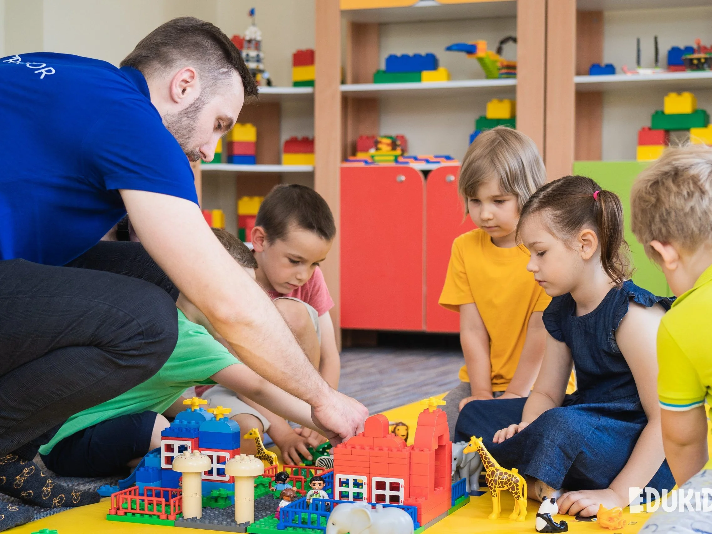Lektor s dětmi staví ze stavebnice LEGO Duplo model zoo