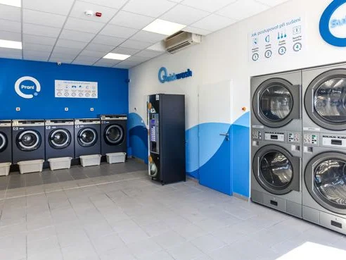 Interiér samoobslužné prádelny Quickwash s pračkami a sušičkami