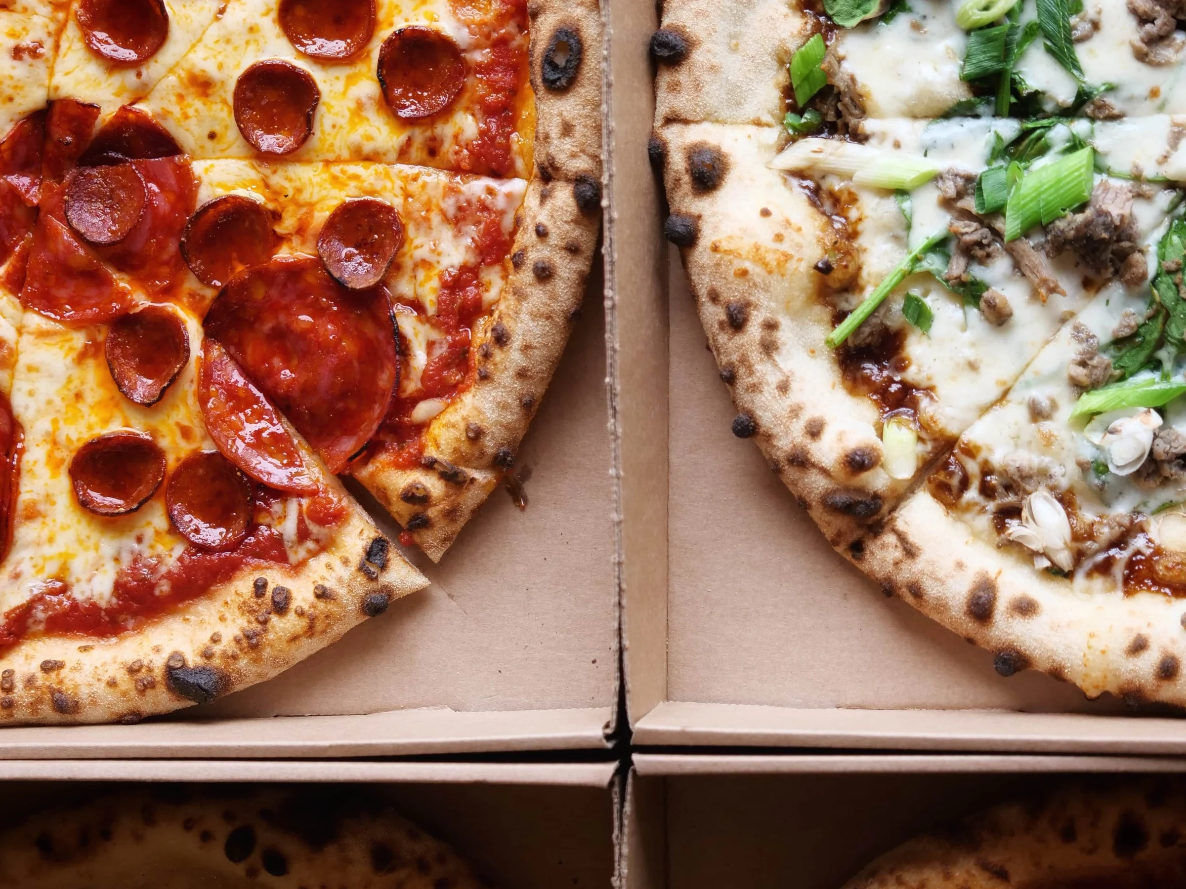 Čtyři druhy pizzy v krabicích připravené k rozvozu