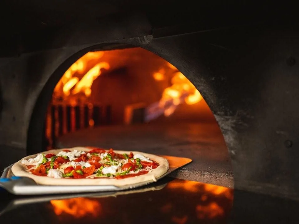 Pizza na lopatě před rozpálenou pecí
